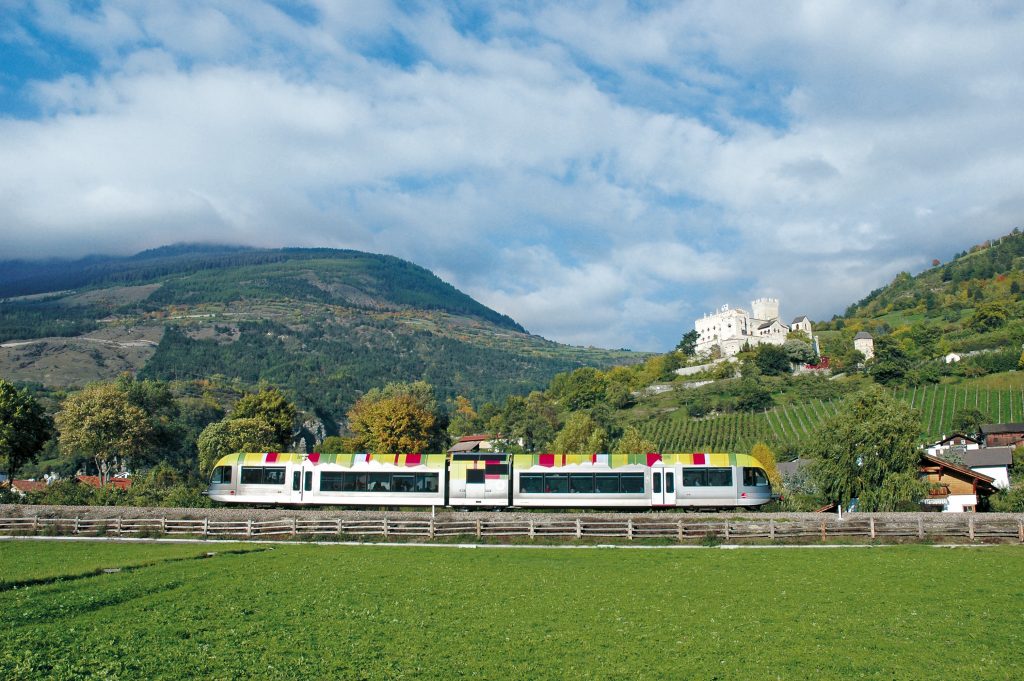 A Dolomites train project could be ready for the 2026 Olympics. This train is one working at Sudtirol. IDM Sudtirol. Photo: Hans-Peter Leu. A unique experience is provided by the new railway line from Merano/Meran to Malles/Mals: the train brings you to Malles, where you can rent a bike and return slightly downhill alongside the orchards and ancient sites of the old Roman trade route Via Claudia Augusta.